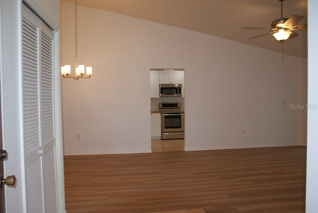 A room with light wood-look flooring, a ceiling fan, and a doorway to a kitchen — 7445 CRESTWOOD DRIVE, WEEKI WACHEE, FL