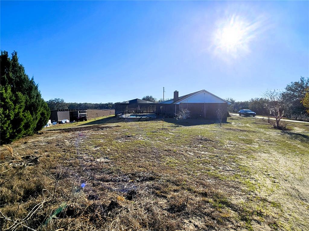 A view of a house with a screened pool enclosure and a detached shed — 13308 DUCK LAKE CANAL ROAD, DADE CITY, FL