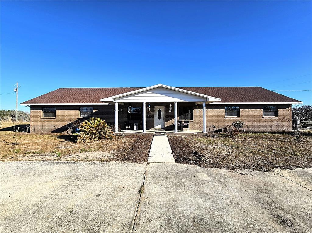 A single-story brick house with a brown shingled roof and a covered front porch — 13308 DUCK LAKE CANAL ROAD, DADE CITY, FL