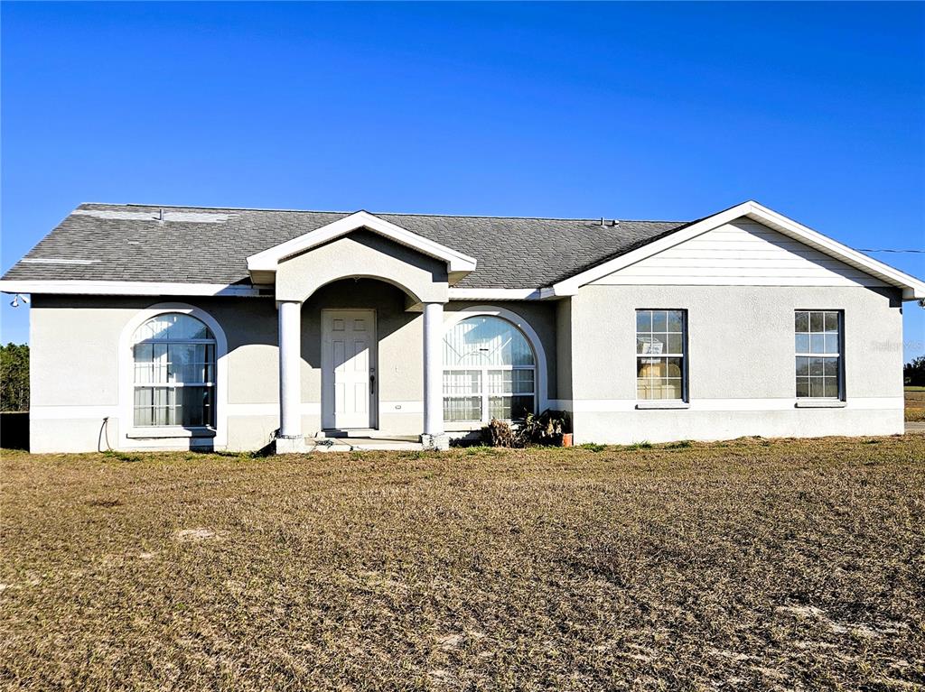 A single-story house with a gray exterior, arched windows, and a covered front entryway — 13308 DUCK LAKE CANAL ROAD, DADE CITY, FL
