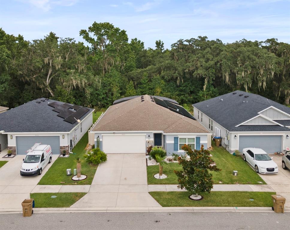 An aerial view shows three suburban houses with driveways and solar panels on their roofs — 4521 CASABLANCA AVENUE, KISSIMMEE, FL