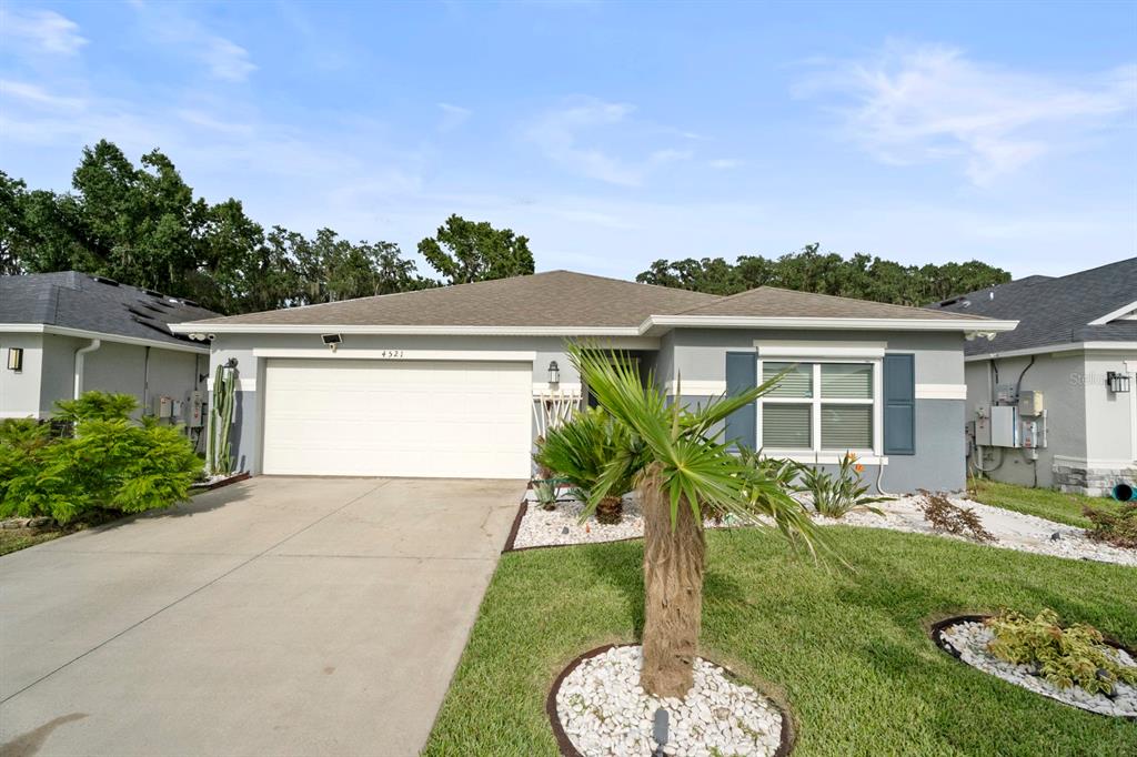 A single-story house with a two-car garage, gray siding, and a landscaped front yard — 4521 CASABLANCA AVENUE, KISSIMMEE, FL