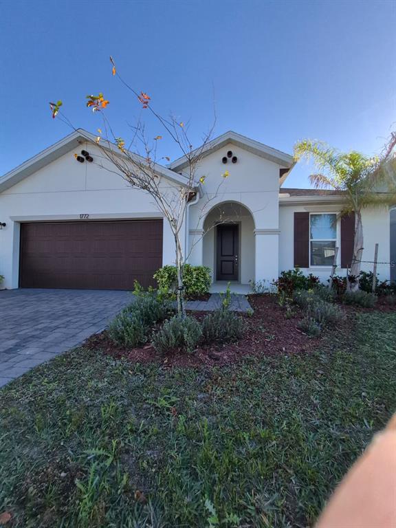 A single-story house with a brown garage door, a covered entryway, and a palm tree — 1772 STAMEN DRIVE, KISSIMMEE, FL