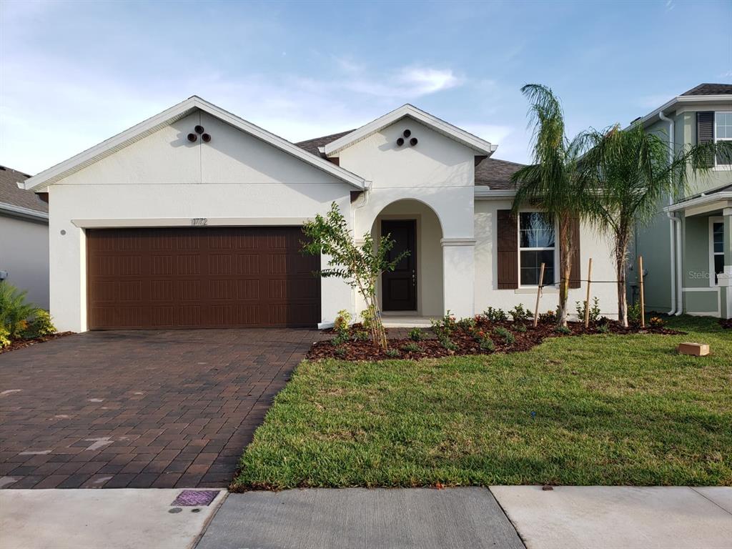 A single-story house with a white stucco exterior, brown garage door, and a paved driveway — 1772 STAMEN DRIVE, KISSIMMEE, FL