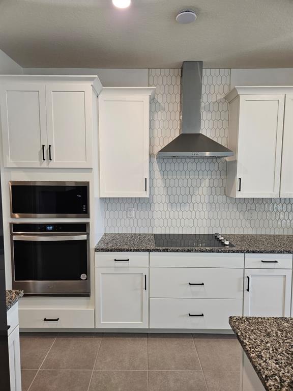 A kitchen features white cabinets, granite countertops, a stainless steel oven, and a tiled backsplash — 1772 STAMEN DRIVE, KISSIMMEE, FL