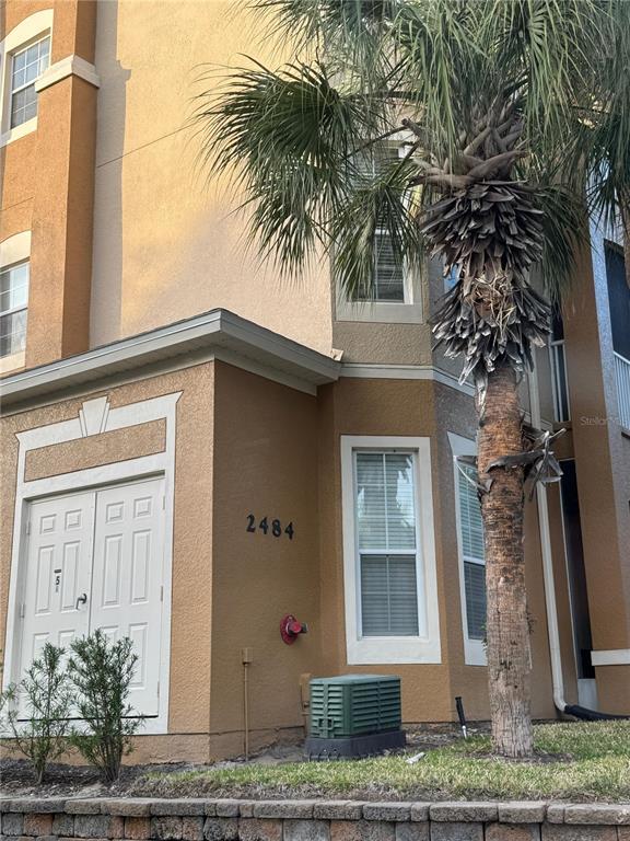 A tan stucco building exterior features a double door, a palm tree, and a utility box — 2484 SAN TECLA STREET UNIT 402, ORLANDO, FL