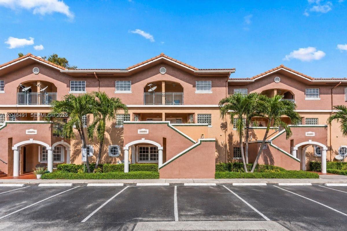 A multi-story tan stucco apartment building with arched entryways and a parking lot in front — 10014 Hammocks Blvd # 4, Miami FL 33196, MIAMI, FL