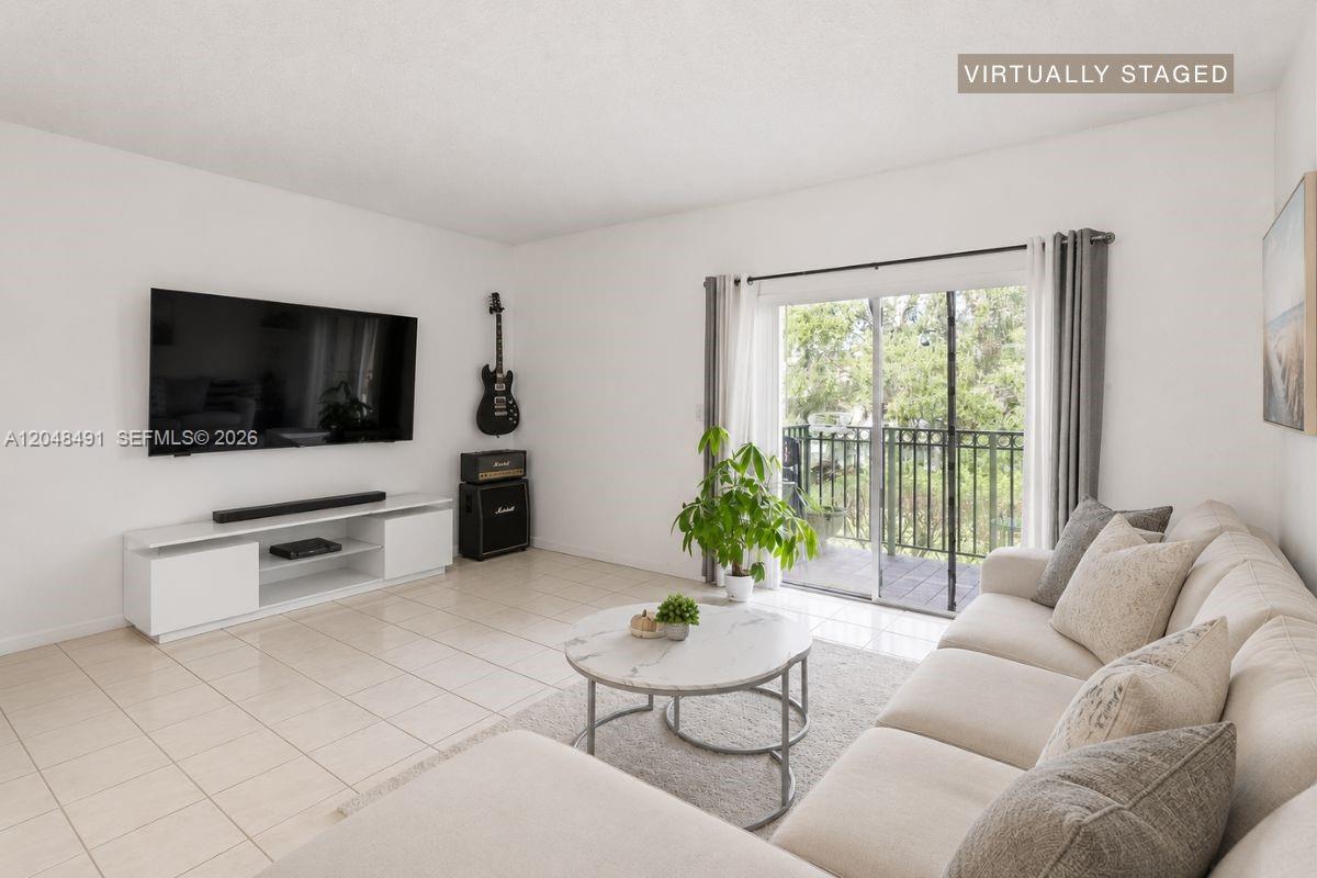 A living room features a white sofa, a round coffee table, and a wall-mounted television — 10014 Hammocks Blvd # 4, Miami FL 33196, MIAMI, FL