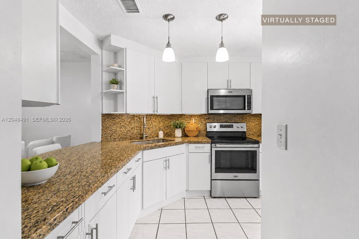 A kitchen features white cabinets, granite countertops, stainless steel appliances, and tile flooring — 10014 Hammocks Blvd # 4, Miami FL 33196, MIAMI, FL