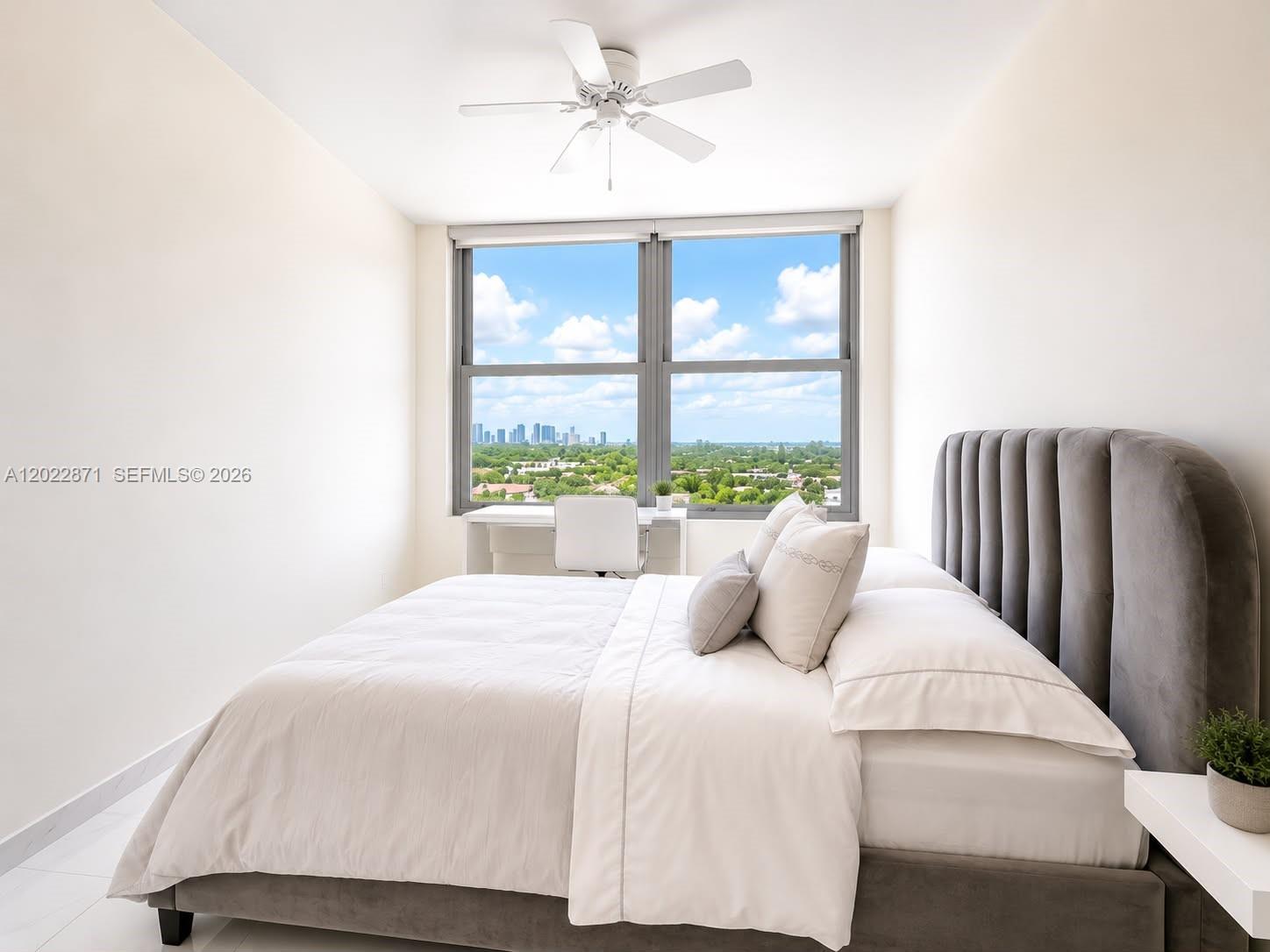 A bedroom features a gray upholstered bed, a white desk, and a city skyline view — 2899 Collins Ave # 1042, Miami Beach FL 33140, MIAMI BEACH, FL