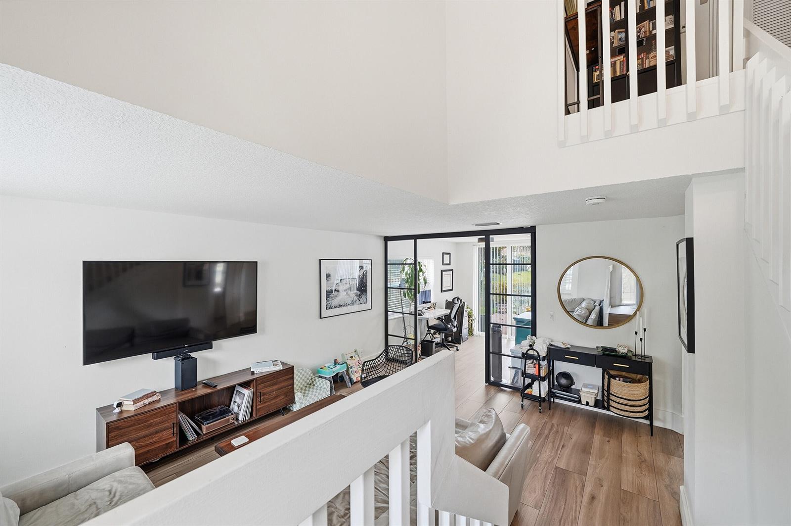 A living room with wood flooring, a television console, and a glass-enclosed office space — 10690 NW 12th Drive, Plantation FL 33322, PLANTATION, FL
