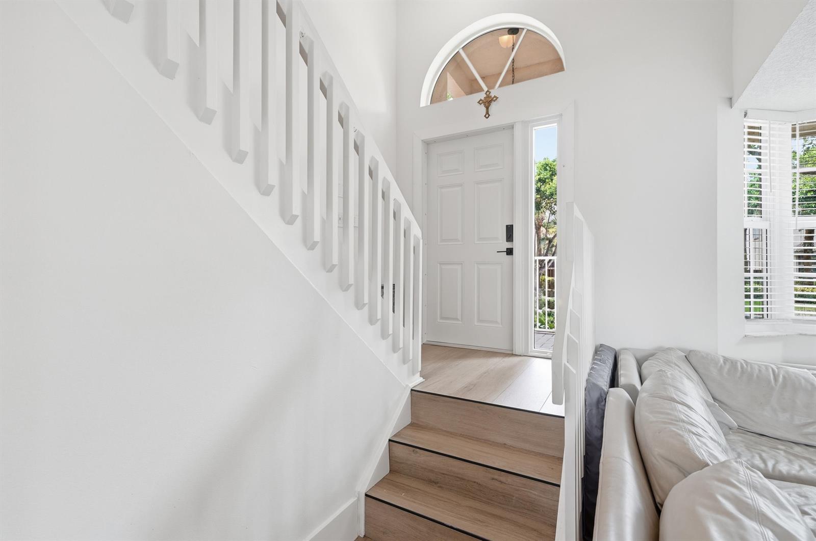 An entryway features a white front door, a staircase with wooden treads, and white railings — 10690 NW 12th Drive, Plantation FL 33322, PLANTATION, FL