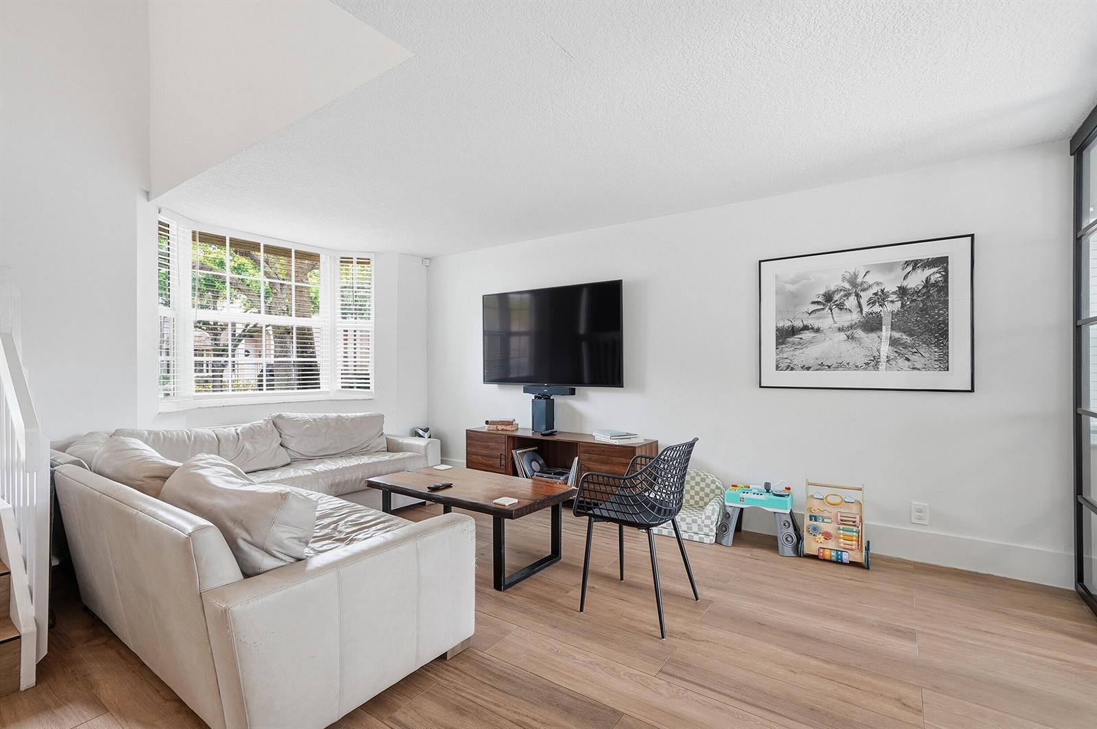 A living room features a white sofa, a wooden coffee table, and a wall-mounted television — 10690 NW 12th Drive, Plantation FL 33322, PLANTATION, FL
