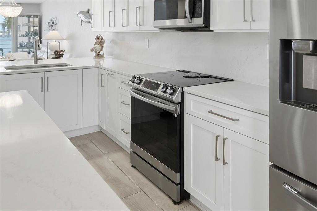 A modern kitchen features white cabinets, stainless steel appliances, and light-colored countertops — 6081 BAHIA DEL MAR CIRCLE UNIT 251, ST PETERSBURG, FL
