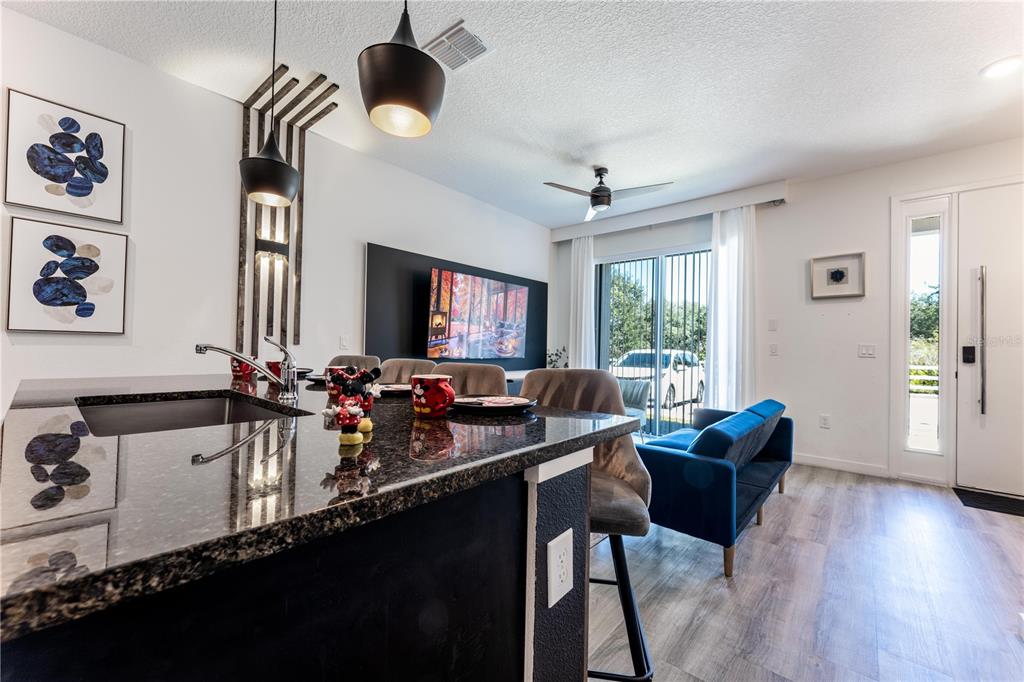 A kitchen island with granite countertops overlooks a living area with a blue sofa — 3405 TRANQUIL TRAIL, KISSIMMEE, FL