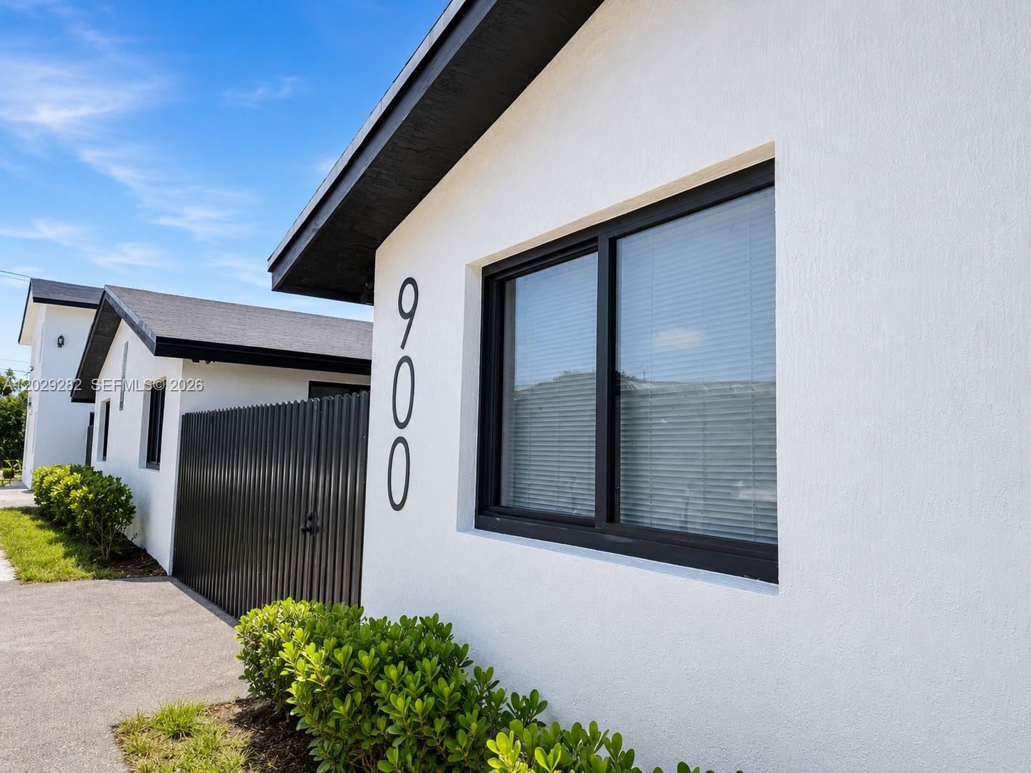 The exterior of a white house features black window frames, a dark fence, and address numbers — 900 NW 8th Ave # 4, Pompano Beach FL 33060, POMPANO BEACH, FL