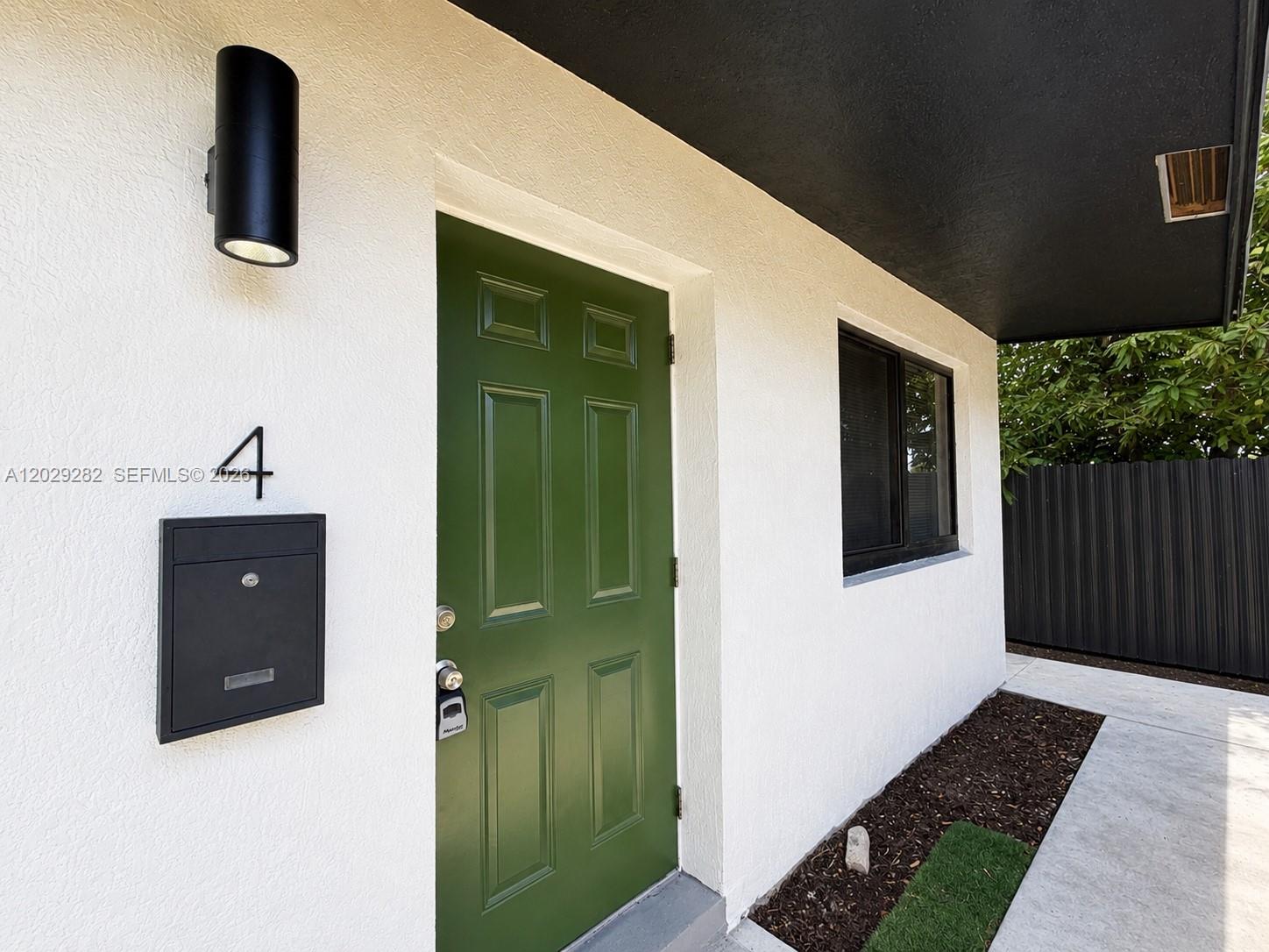 A green front door with a black mailbox and light fixture on a white wall — 900 NW 8th Ave # 4, Pompano Beach FL 33060, POMPANO BEACH, FL