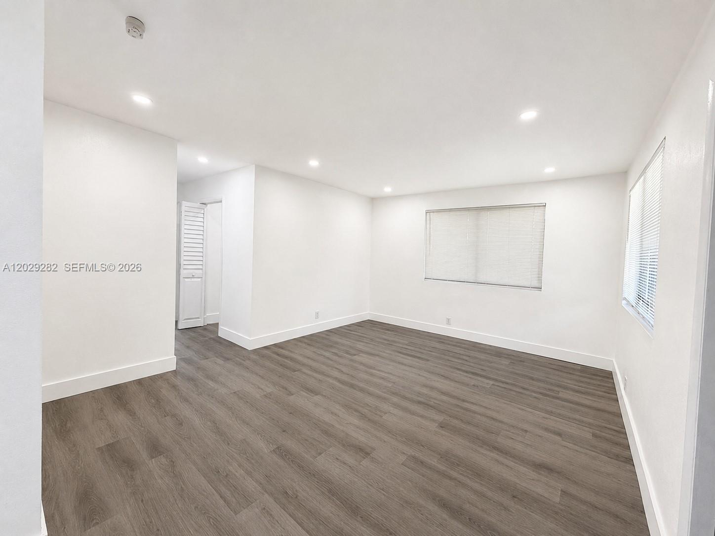 An empty room features white walls, recessed lighting, and gray wood-look flooring — 900 NW 8th Ave # 4, Pompano Beach FL 33060, POMPANO BEACH, FL