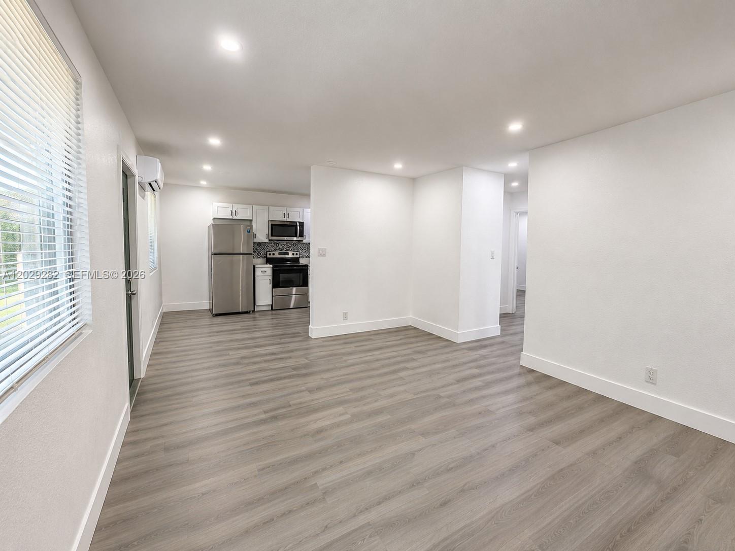 An open-concept living area features light wood-look flooring and a kitchen with stainless steel appliances — 900 NW 8th Ave # 4, Pompano Beach FL 33060, POMPANO BEACH, FL