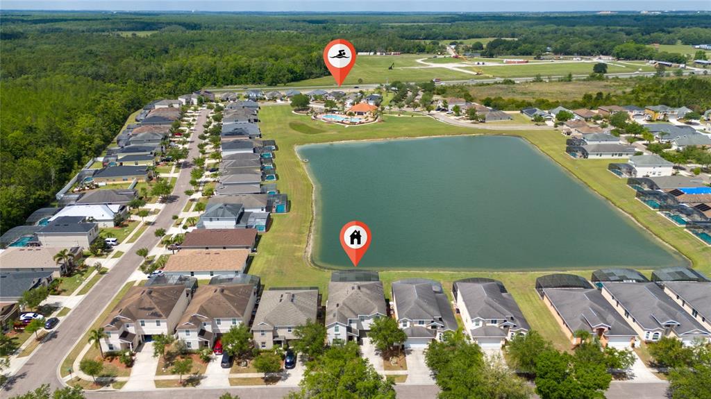 A two-story beige house with a two-car garage, a palm tree, and a concrete driveway — 1006 TOURMALINE DRIVE, KISSIMMEE, FL