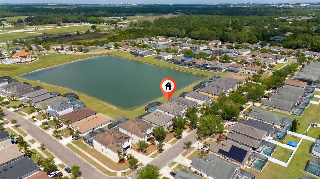 An aerial view shows a suburban neighborhood with houses surrounding a large central lake — 1006 TOURMALINE DRIVE, KISSIMMEE, FL
