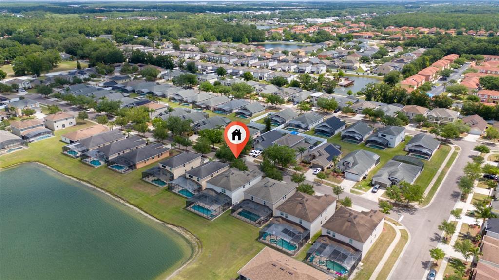 An aerial view shows a residential neighborhood with houses surrounding a large central lake — 1006 TOURMALINE DRIVE, KISSIMMEE, FL