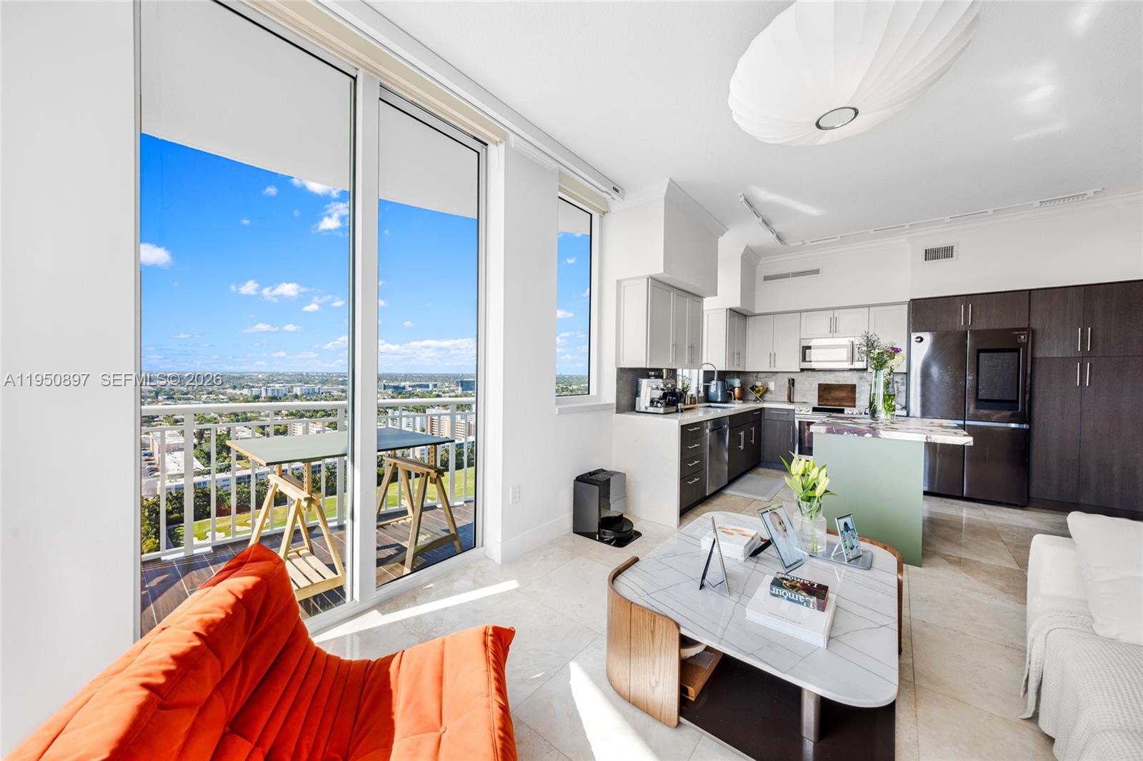 A modern living room and kitchen area features a balcony with city views — 1745 E Hallandale Beach Blvd # 2407W, Hallandale Beach FL 33009, HALLANDALE BEACH, FL