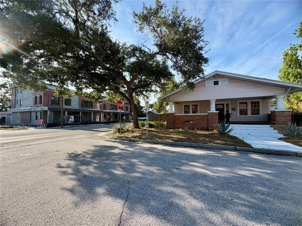A single-story house with a brick porch stands beside a large tree and construction site — 419 W PARK AVENUE, TAMPA, FL