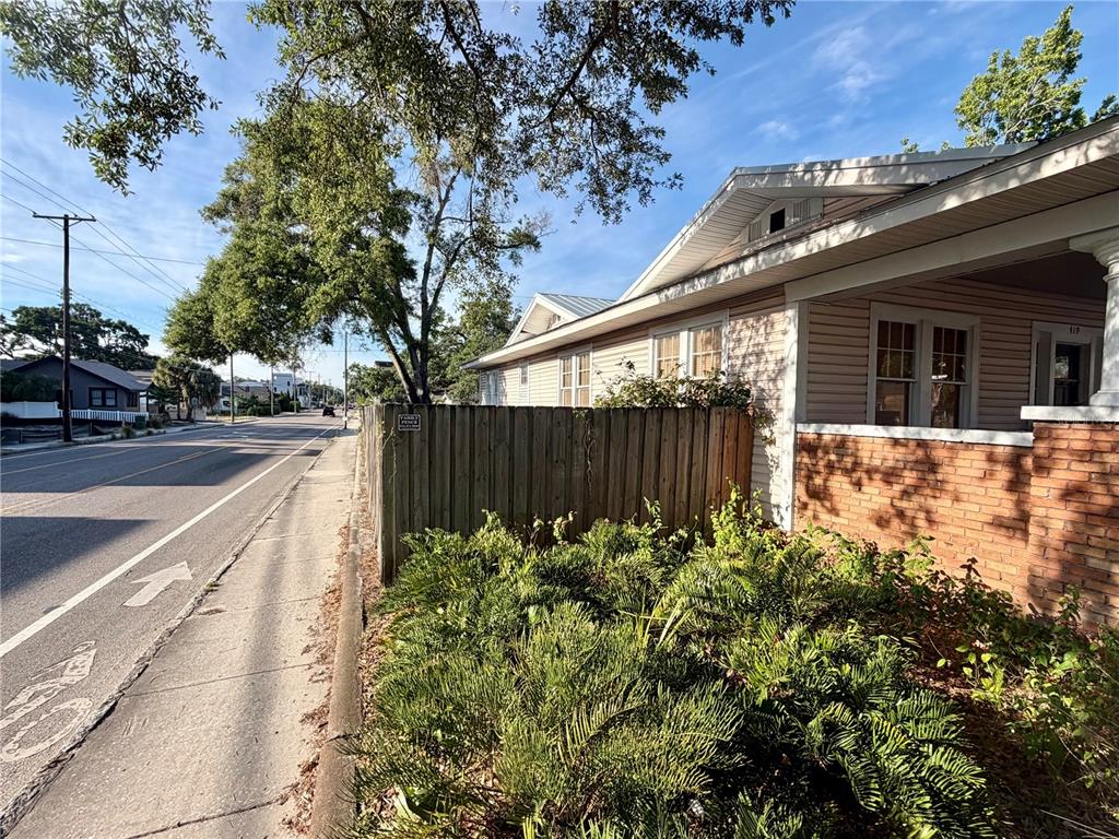 A wooden fence borders the side of a house with brick and siding exterior — 419 W PARK AVENUE, TAMPA, FL
