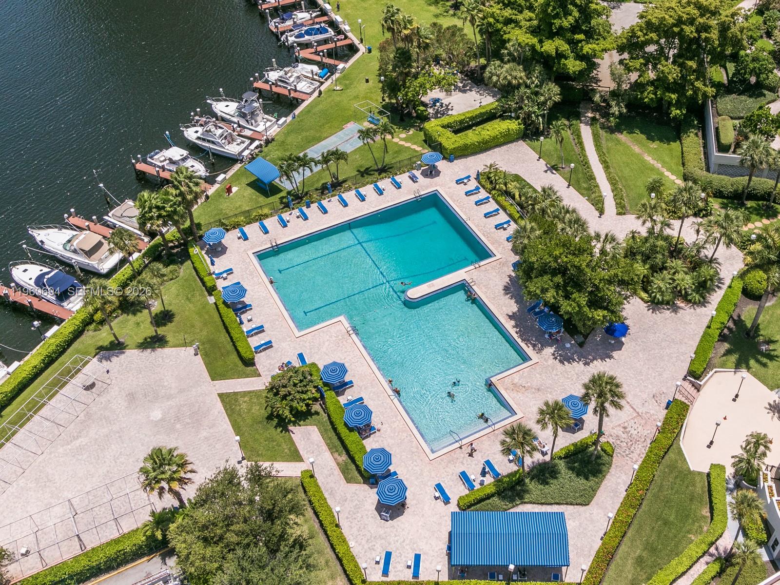 An aerial view shows a swimming pool with lounge chairs and a nearby boat dock — 600 Three Islands Blvd # 411, Hallandale Beach FL 33009, HALLANDALE BEACH, FL