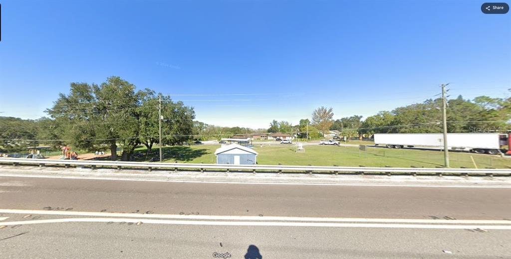 A grassy lot with a small shed and playground equipment sits beside a paved road — N/A, POLK CITY, FL