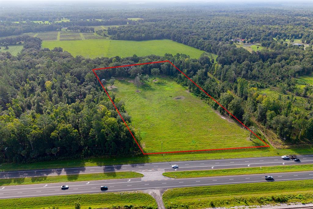 An aerial view shows a rectangular, grassy vacant lot outlined in red next to a highway — TBD 000 SE HWY 301, HAWTHORNE, FL