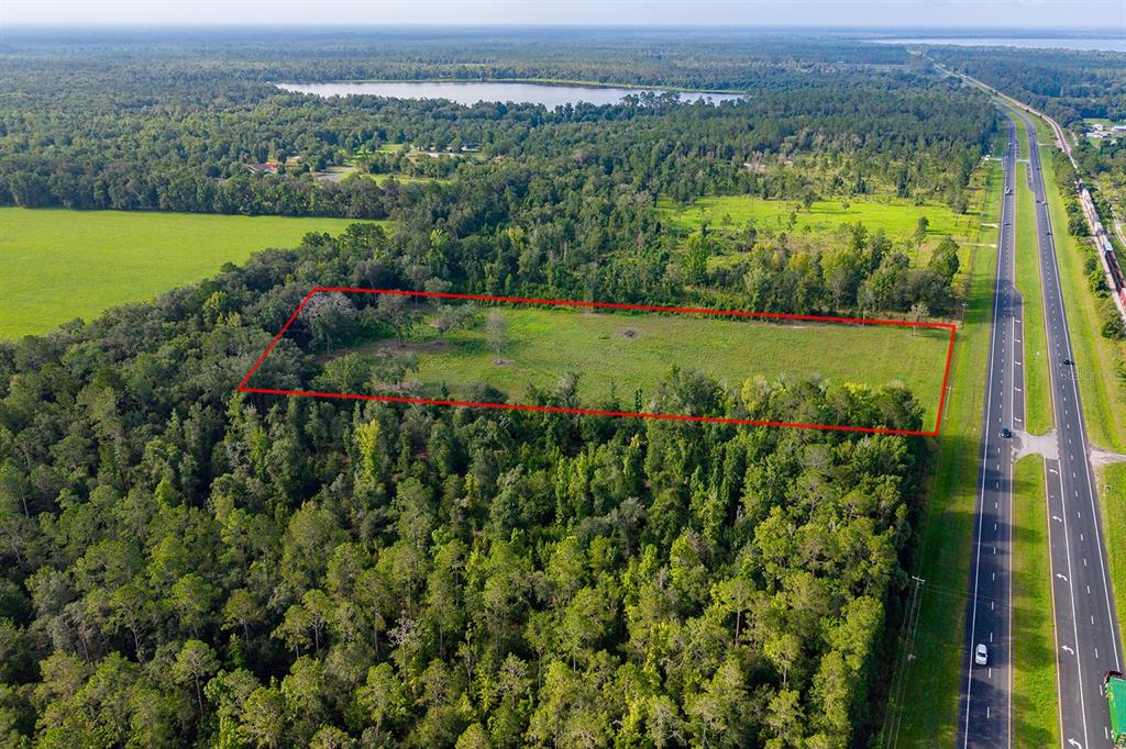 An aerial view shows a rectangular plot of cleared land bordered by trees and a highway — TBD 000 SE HWY 301, HAWTHORNE, FL