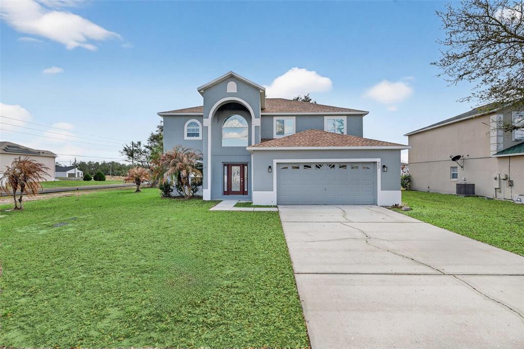 A two-story, blue-gray suburban house with a two-car garage and a concrete driveway — 402 BIG SIOUX COURT, KISSIMMEE, FL
