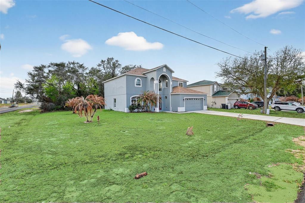 A two-story gray house with a two-car garage sits on a large grassy lot — 402 BIG SIOUX COURT, KISSIMMEE, FL