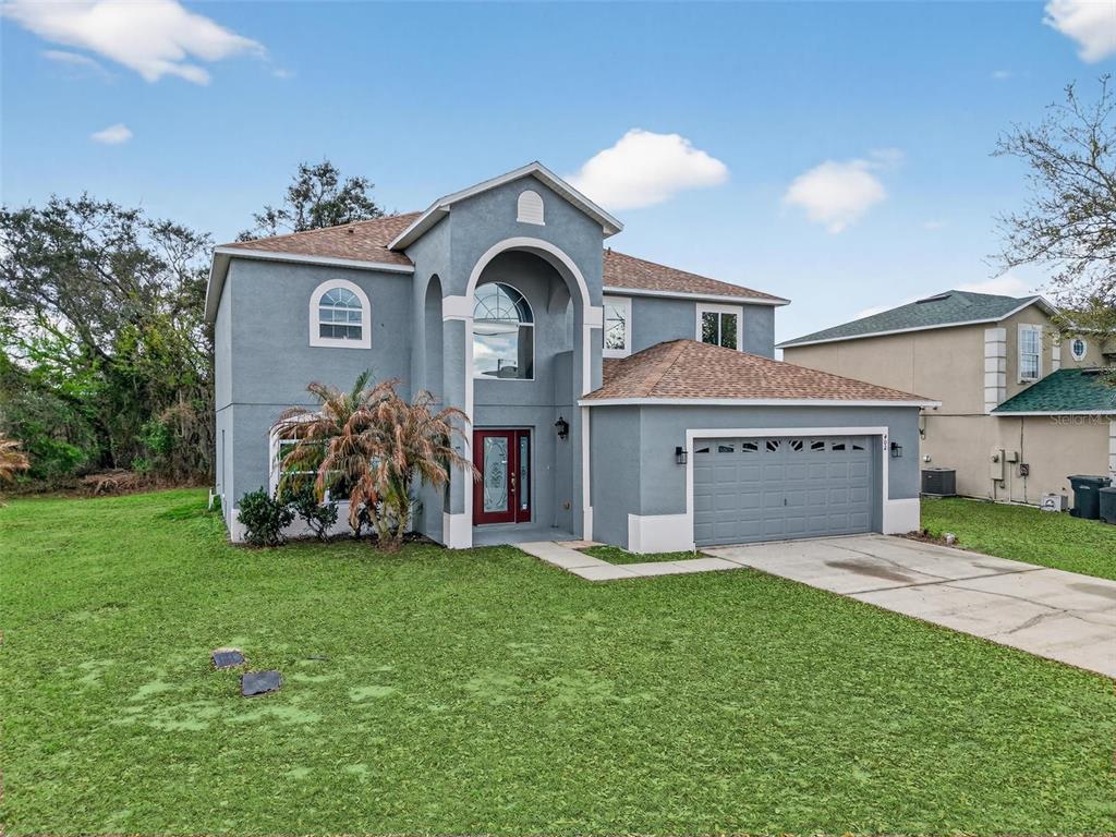 A two-story blue house with a gray garage and a red front door — 402 BIG SIOUX COURT, KISSIMMEE, FL