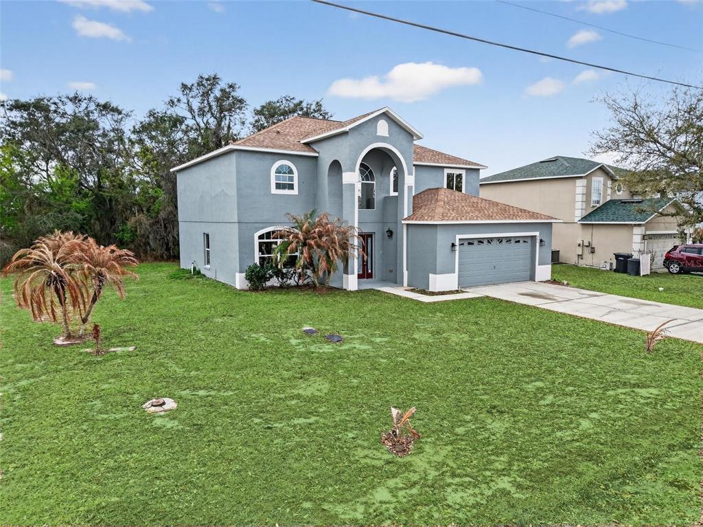 A two-story, blue-gray stucco house with a two-car garage and a large front lawn — 402 BIG SIOUX COURT, KISSIMMEE, FL