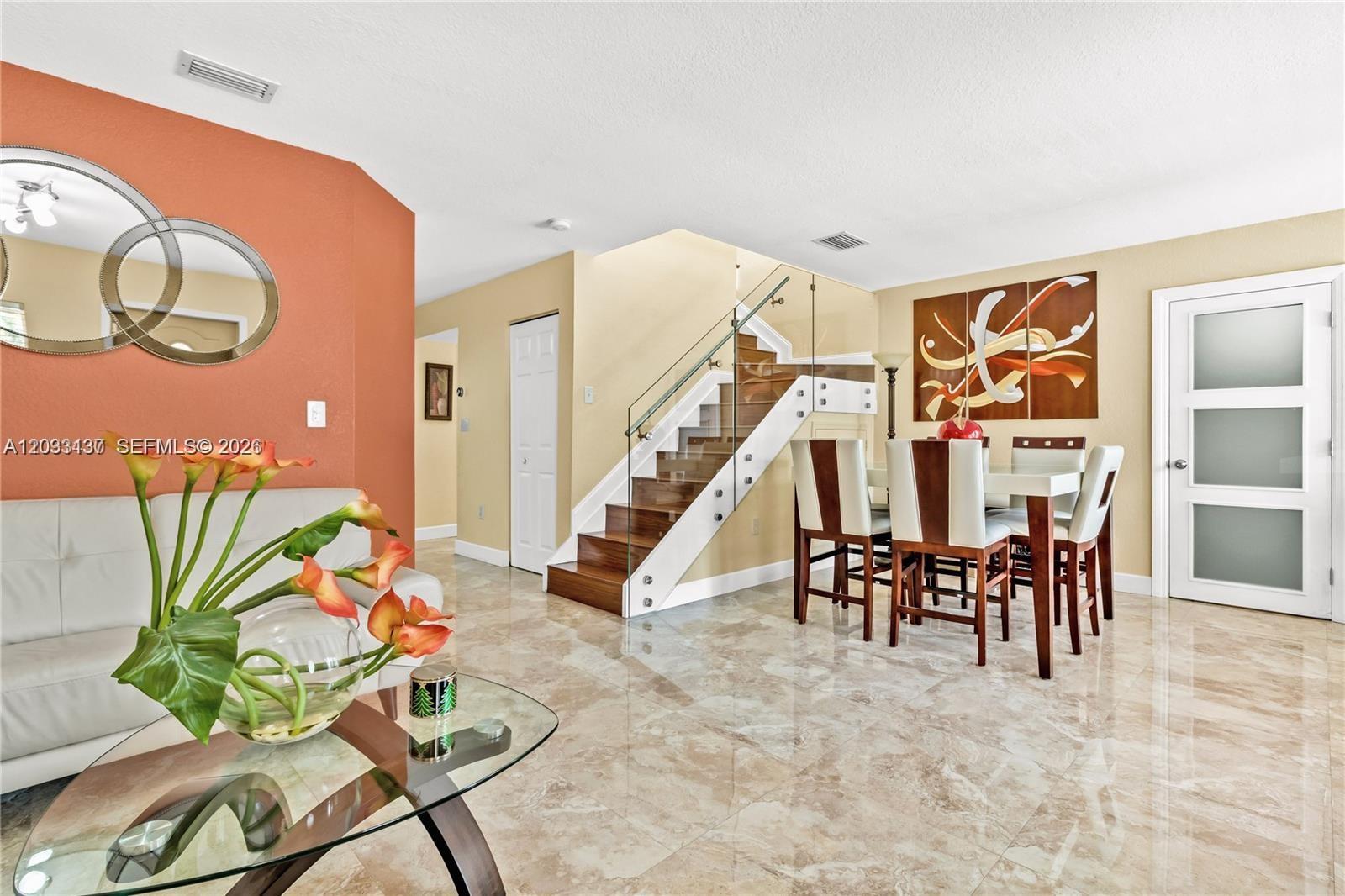 A dining area and living space feature marble floors, a glass-railed staircase, and modern furniture — 16453 SW 97th St # 0, Miami FL 33196, MIAMI, FL