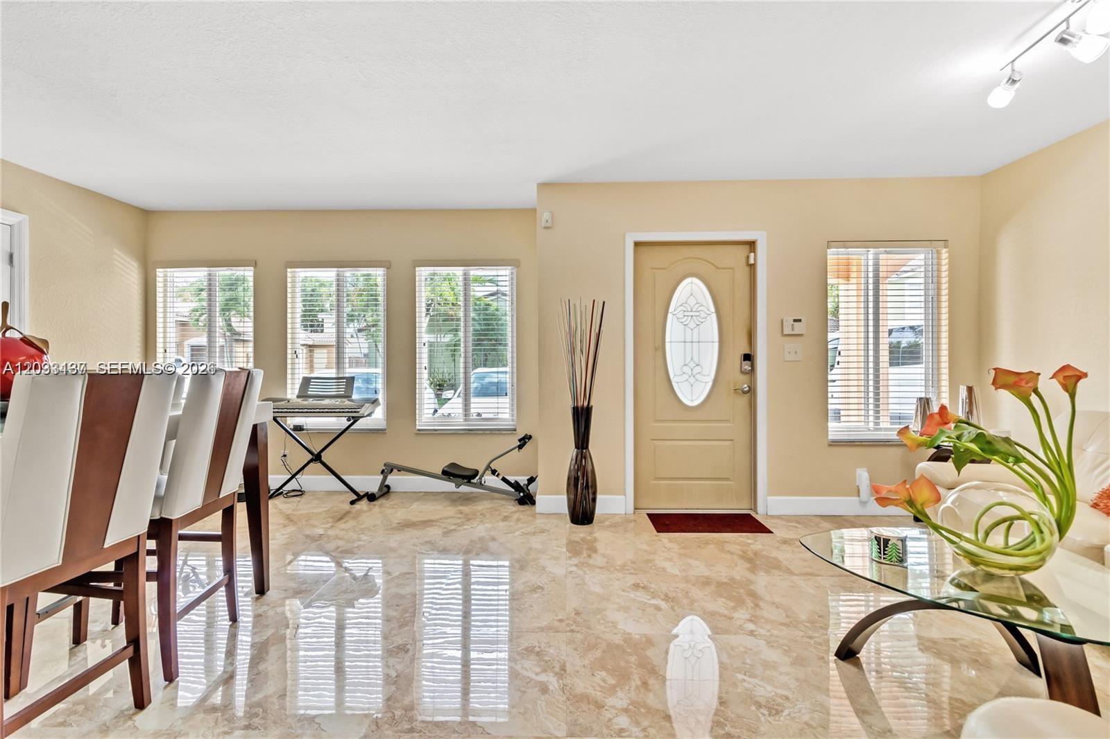 A living and dining area features beige walls, marble-look tile flooring, and a front door — 16453 SW 97th St # 0, Miami FL 33196, MIAMI, FL