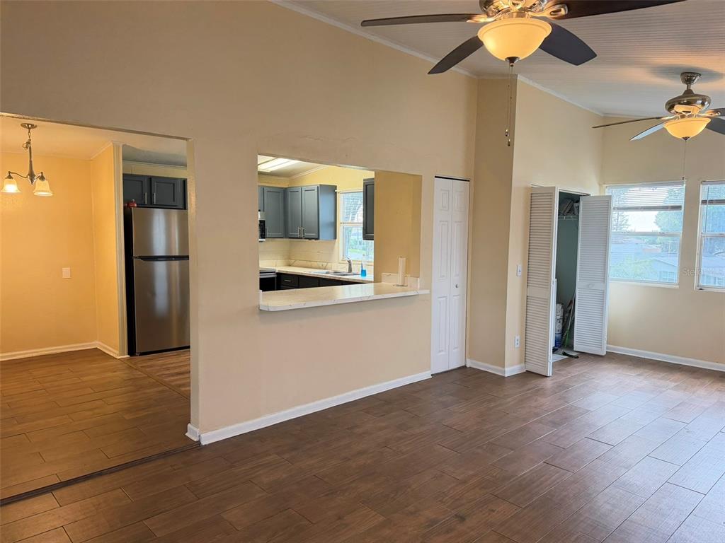 A living room with wood-look tile flooring, a ceiling fan, and a pass-through to the kitchen — 50989 HIGHWAY 27 UNIT 33, DAVENPORT, FL