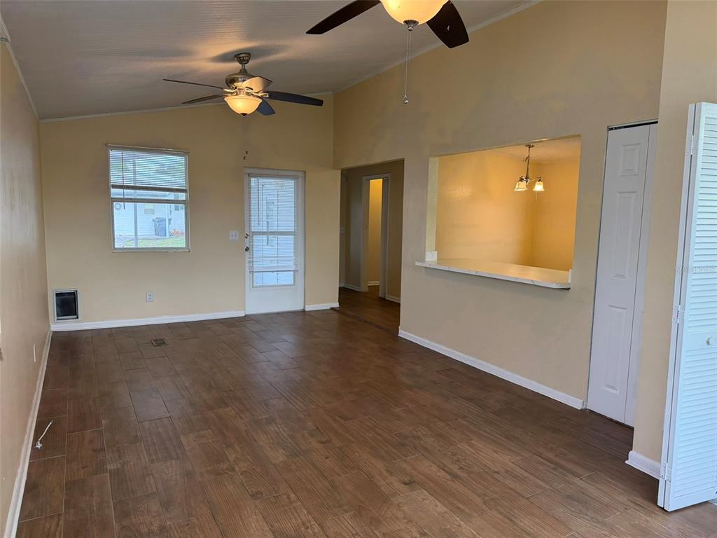 A living room with wood-look tile flooring, a ceiling fan, and a kitchen pass-through window — 50989 HIGHWAY 27 UNIT 33, DAVENPORT, FL