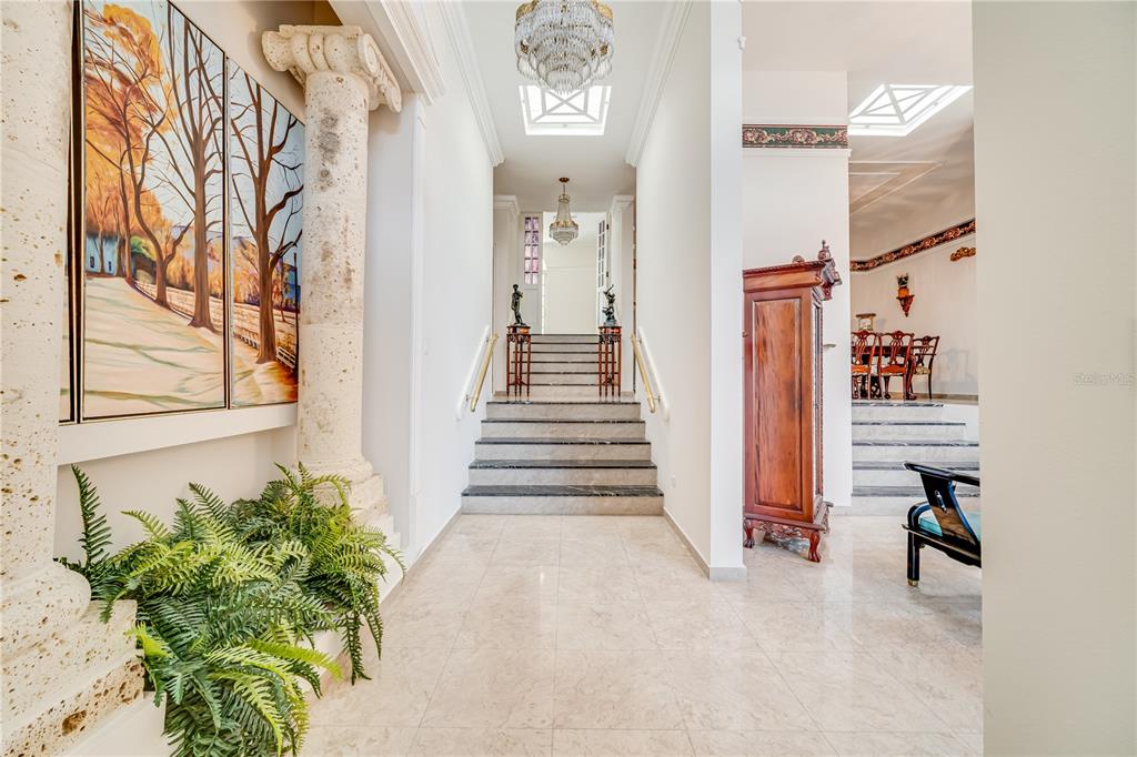 A marble-floored foyer features a grand staircase, a stone pillar, and a crystal chandelier — Cll 1 STREET UNIT 602, GUAYNABO, PR