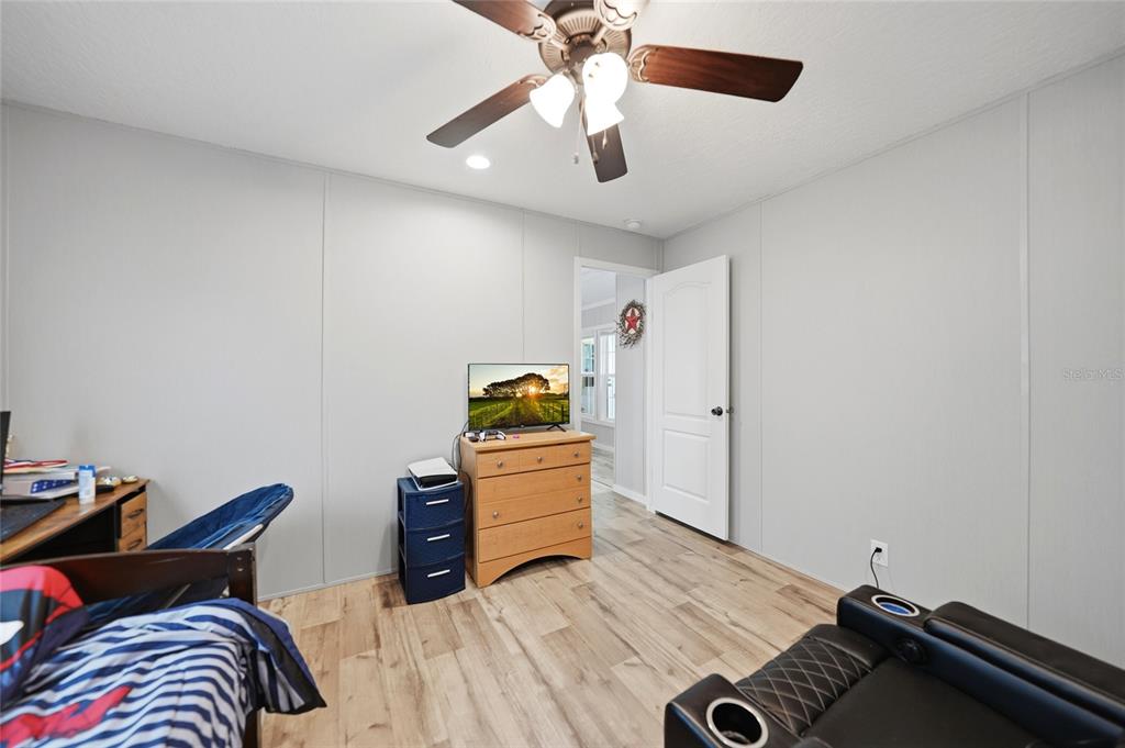 A bedroom with light gray walls, wood-look flooring, a ceiling fan, and a wooden dresser — 11587 SE FOSTER AVENUE, ARCADIA, FL