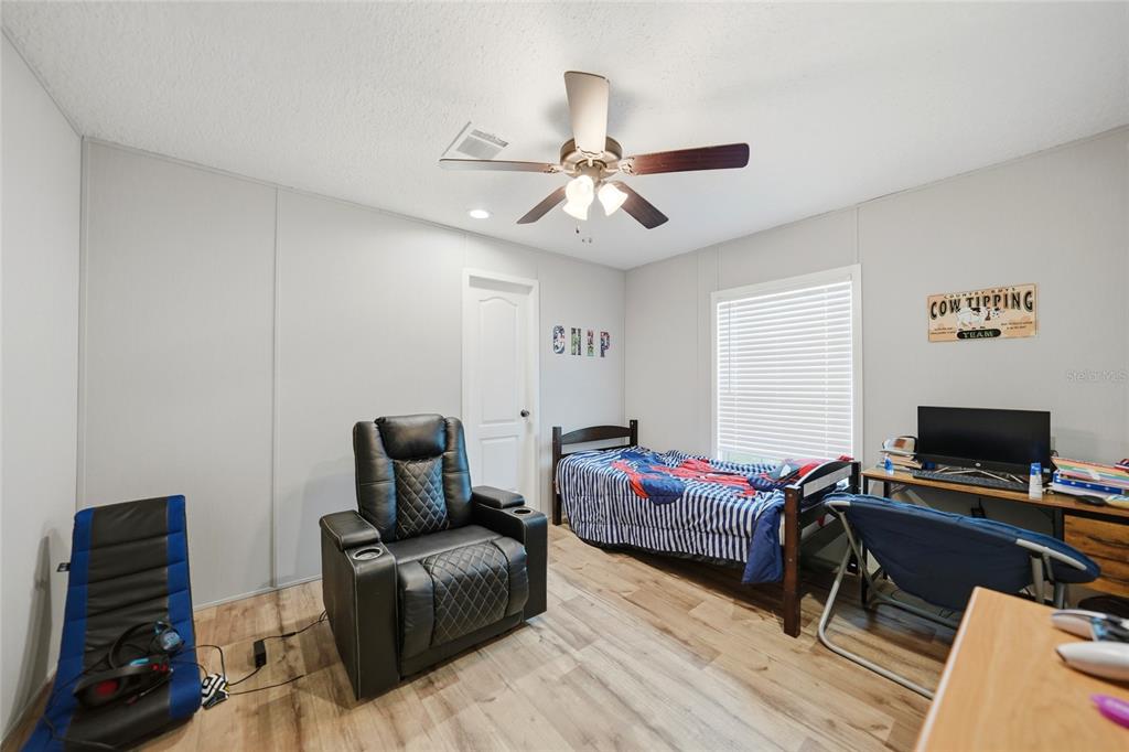 A bedroom features light gray walls, wood-look flooring, a ceiling fan, and a twin bed — 11587 SE FOSTER AVENUE, ARCADIA, FL