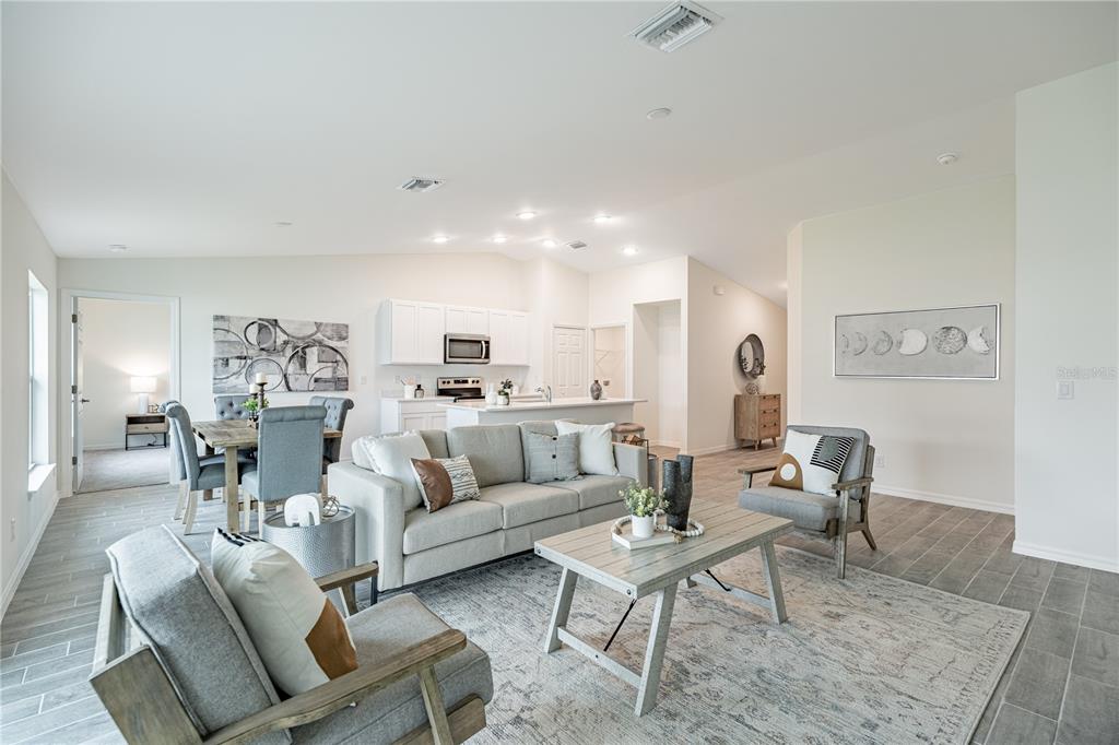 An open-concept living room and kitchen feature gray tile flooring and neutral-toned furniture — 5202 BRUNSWICK TERRACE, PORT CHARLOTTE, FL