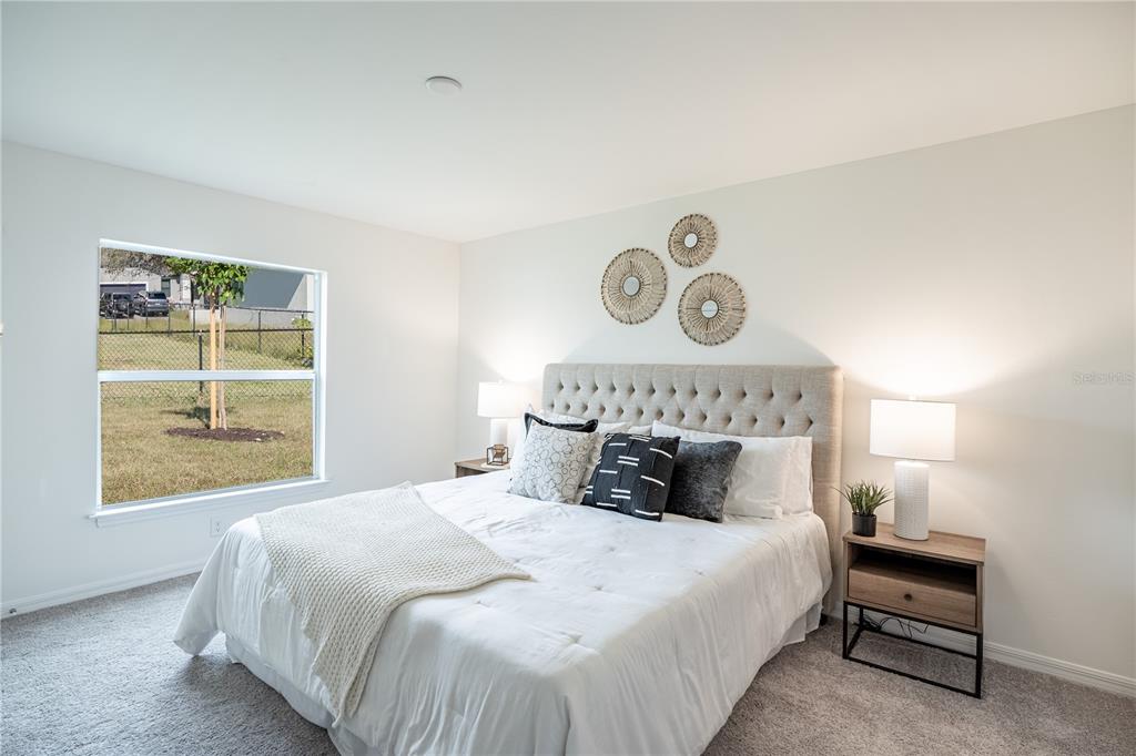 A bedroom features a tufted headboard, two nightstands, and a window overlooking a fenced yard — 5202 BRUNSWICK TERRACE, PORT CHARLOTTE, FL