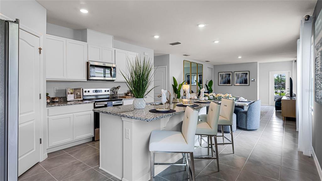 A kitchen with white cabinets, granite countertops, a center island, and bar stools — 35492 SUNFLOWER HILL DRIVE, ZEPHYRHILLS, FL