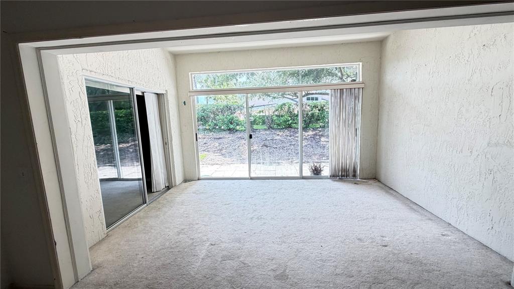 A sunroom with beige carpet, textured walls, and two sets of sliding glass doors — 1 ENCLAVE DRIVE, WINTER HAVEN, FL