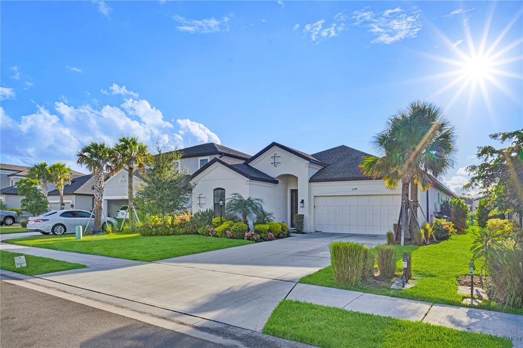 A single-story suburban house with a white stucco exterior, a two-car garage, and palm trees — 6378 GRANDVIEW HILL COURT, BRADENTON, FL