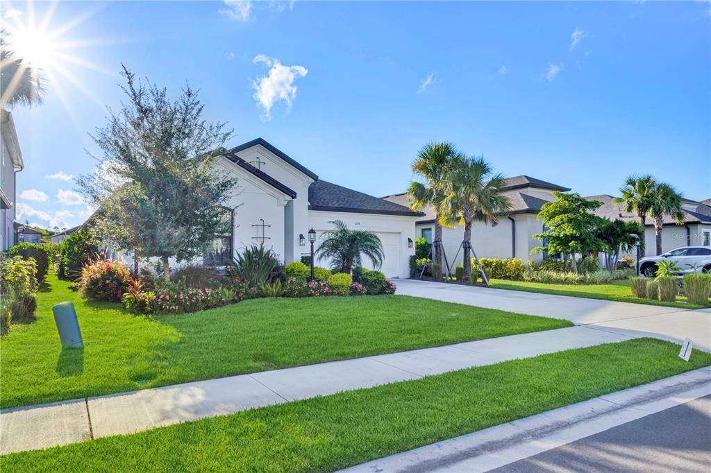 A single-story house with a white stucco exterior, a manicured lawn, and palm trees — 6378 GRANDVIEW HILL COURT, BRADENTON, FL